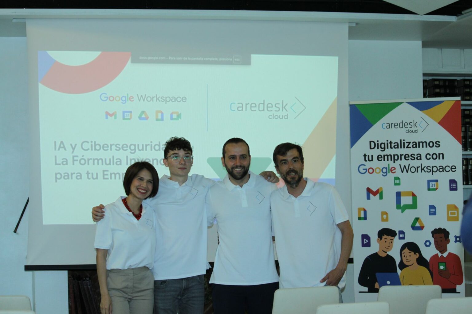 Equipo de CareDesk Cloud posando junto a la presentación y el roll-up del evento