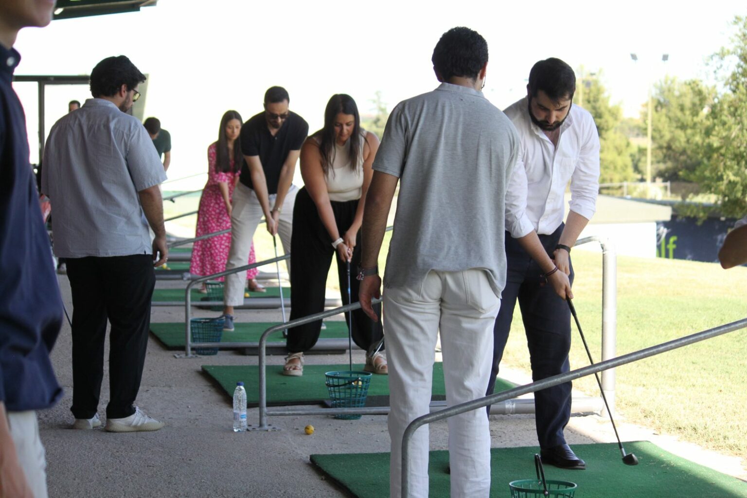Asistentes practicando el swing en la zona de prácticas del club de golf